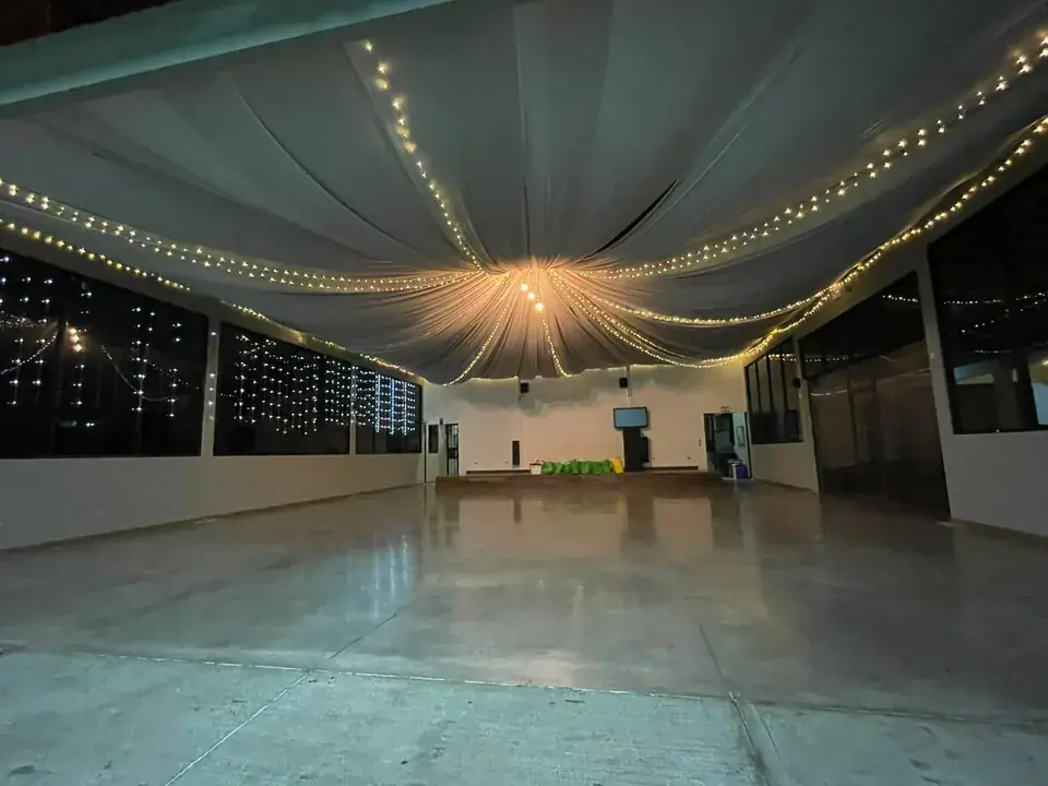 Salón con cortinas blancas y luces cálidas listo para una boda